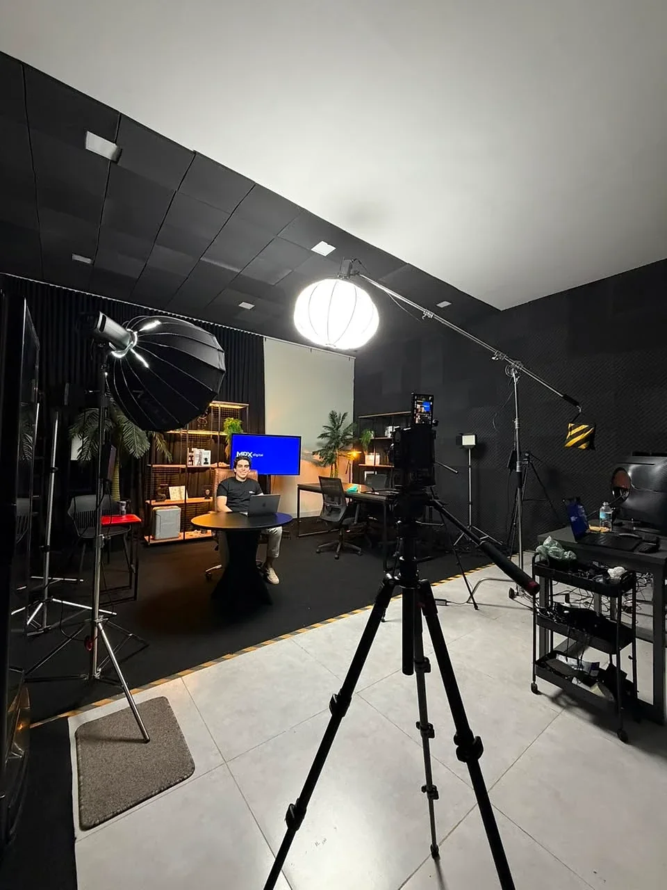 Estúdio da MPX Digital montado para gravação, com iluminação, câmera e o sistema exibido na tela ao fundo